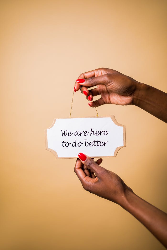 gallery-1 Hands holding sign with motivational message against beige background.