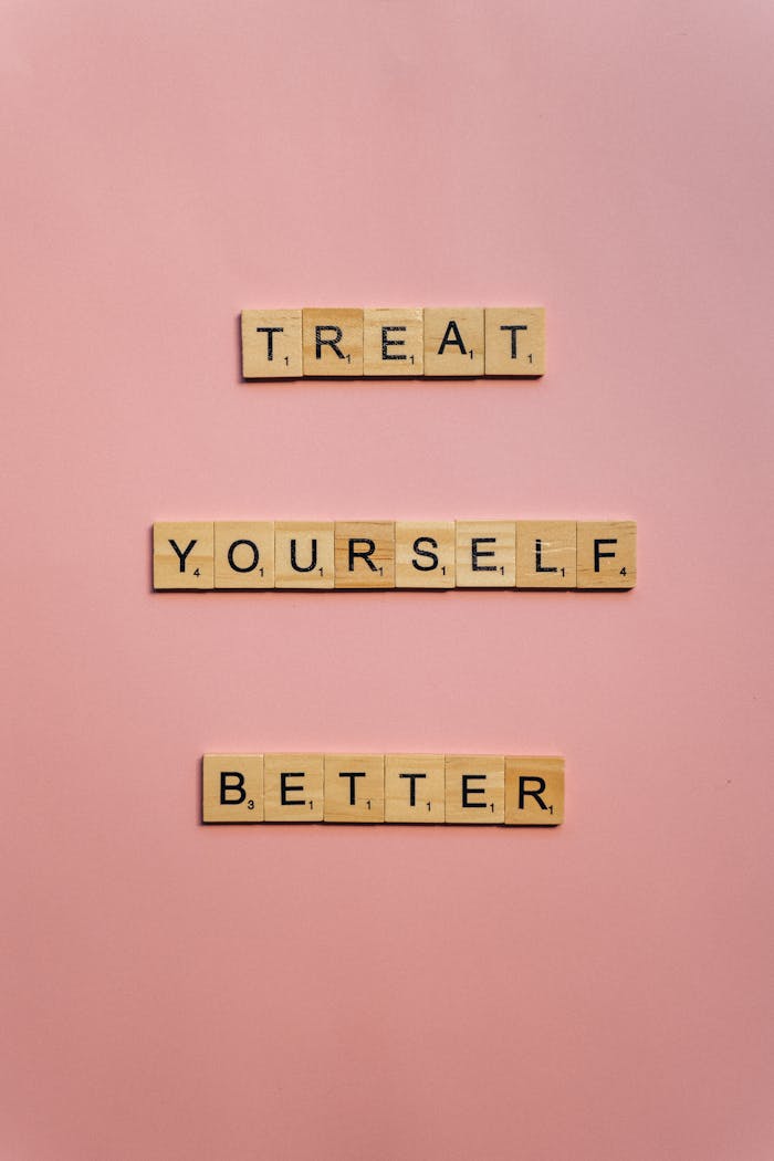 gallery-2 Scrabble tiles spelling 'Treat Yourself Better' on a pink background.