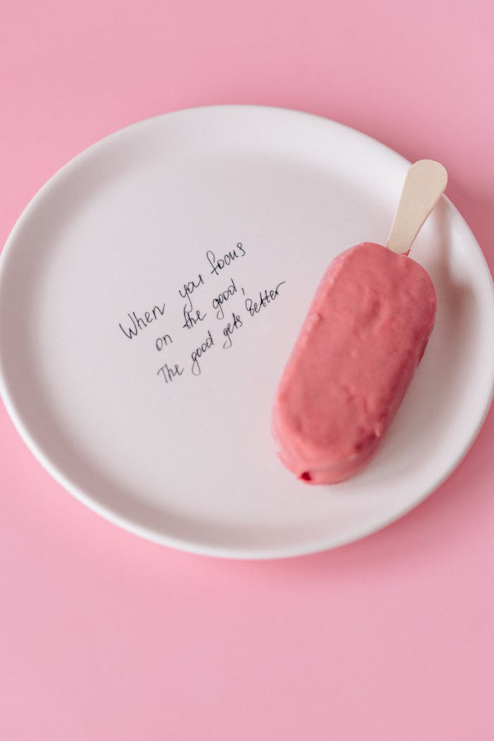 services-03 Ceramic plate with motivational quote and pink popsicle on pink background.